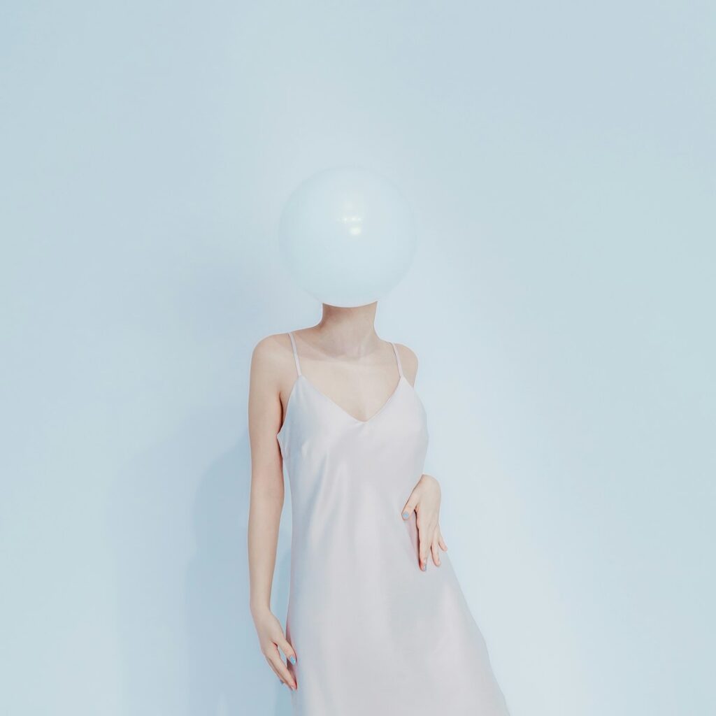 Woman in dress with balloon obscuring face