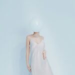 Woman in dress with balloon obscuring face