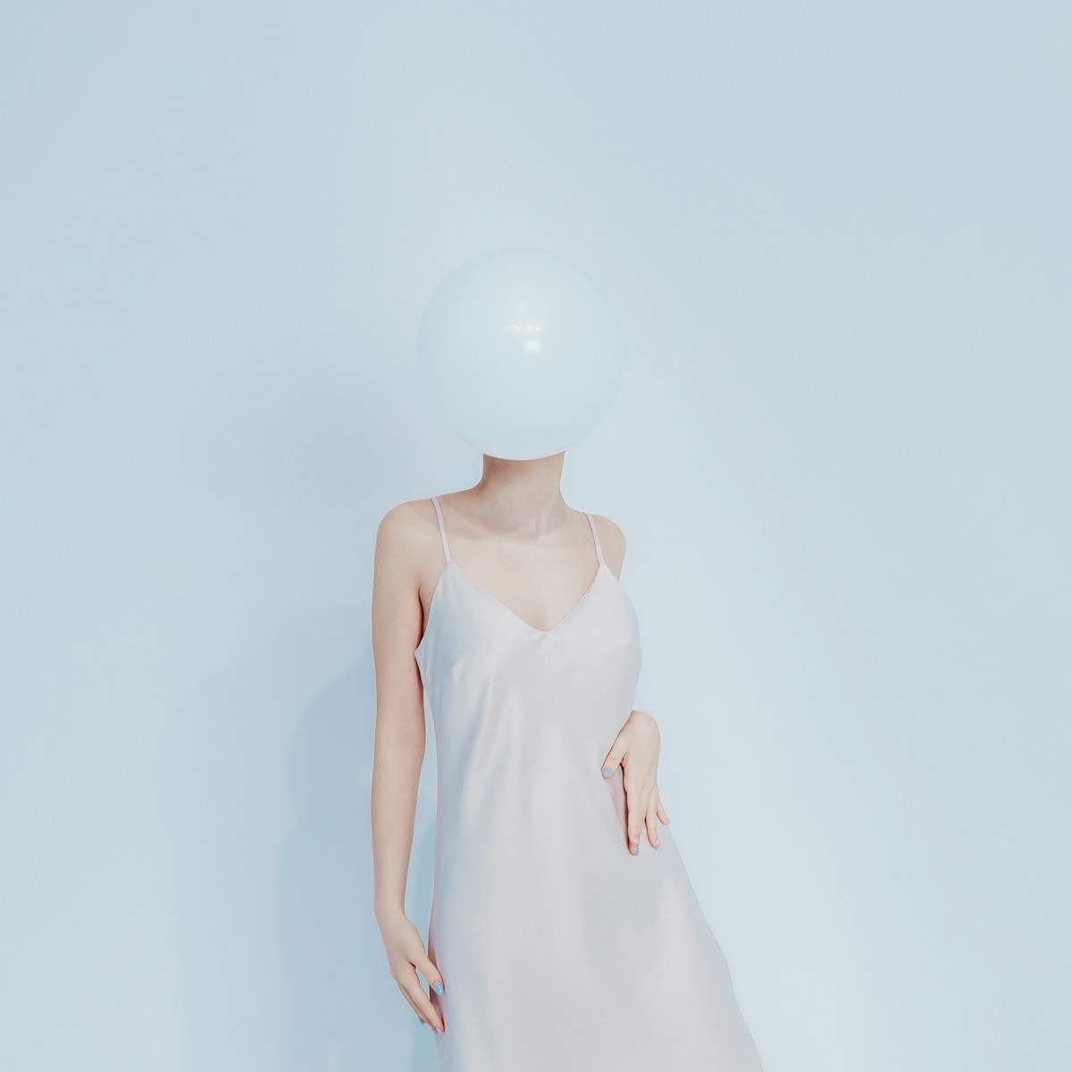 Woman in dress with balloon obscuring face